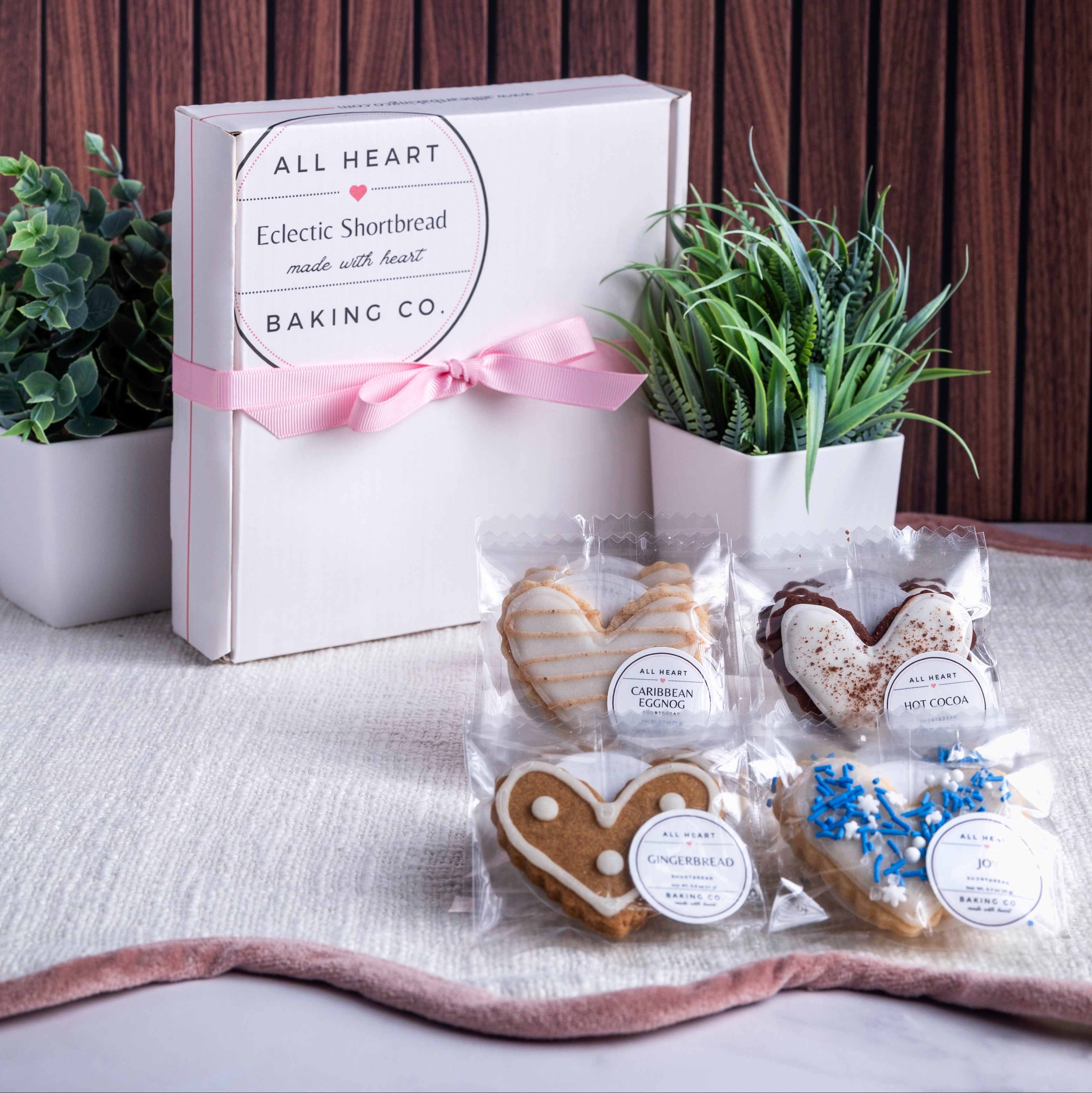 Baked goods in clear packaging with heart shapes, placed on a surface with decorative elements.
