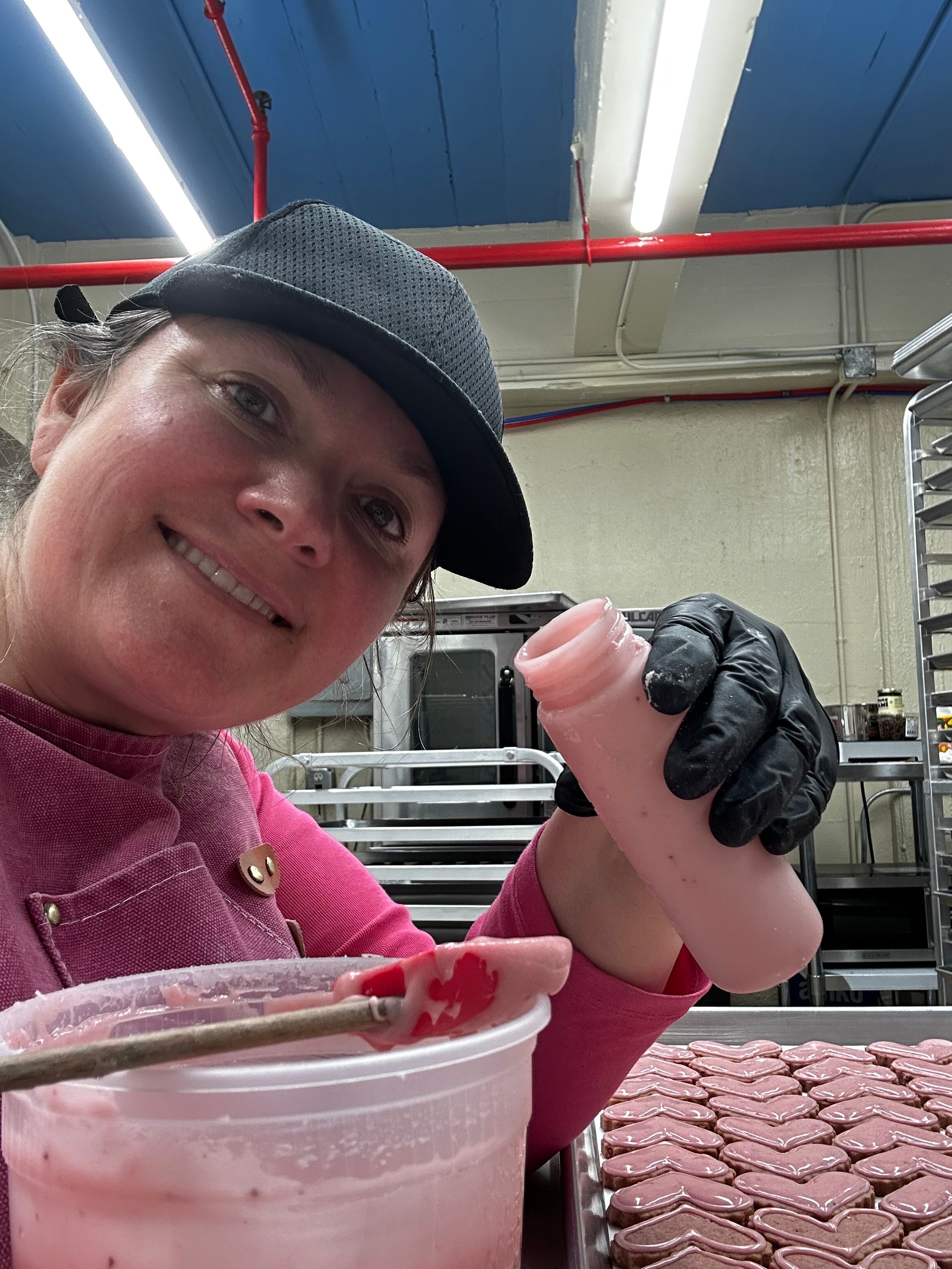 Teresa, owner of All Heart Baking Co., icing heart-shaped shortbread in her kitchen